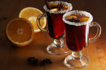 Two cups with ready mulled wine with anise, cinnamon and nuts around
