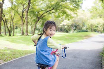 Girl child ride bicycle in green park