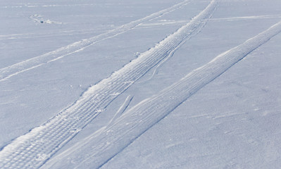 Traces of cars on white snow as a background