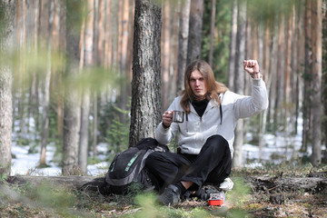 Fototapeta na wymiar A man in a campaign drinks tea. A young traveler in the woods camped and cooked breakfast in nature. The naturalist drinks hot fresh tea cooked on an open fire.