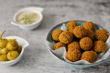 Baked chickpea falafel balls on blue plate on grey background , healthy and vegan food with tahini deep and hot pepper , traditional Mediterranean , top view , flat lay with copy space  