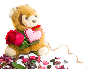 Teddy bear holding a rose and textile pink heart on a white background.The concept of Valentine's Day