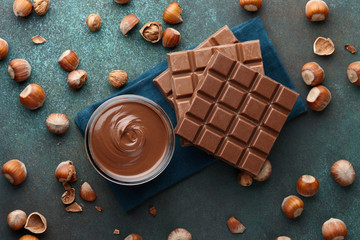 Chocolate spread or nougat cream with hazelnuts in glass jar on blue green textured countertop