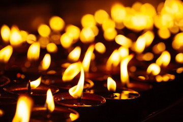 Many candle flames glowing in the dark