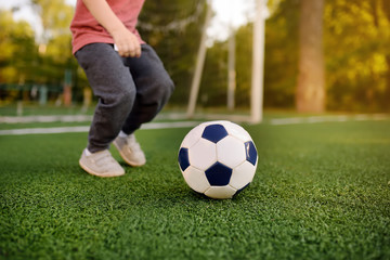 Little boy having fun playing a soccer/football game on summer day. Active outdoors game/sport for...