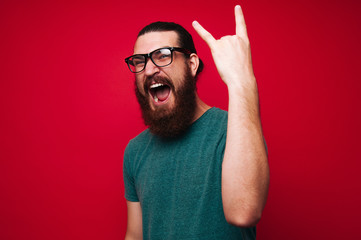 Photo of screaming bearded man gesturing, rock symbol