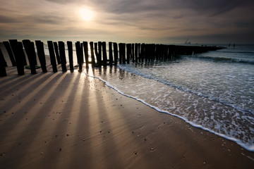 sunshine over old wooden breakwater on North sea coast