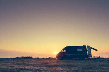 Naklejka na ściany i meble Camper car on nature at sunrise