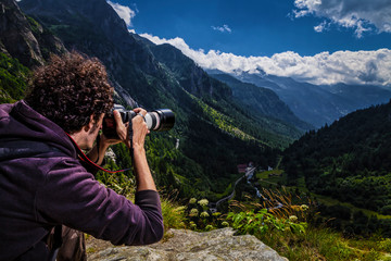 Young man photographing mountain landscape