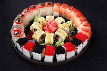 Food art, traditional  japanese seafood, restaurant menu photo. Tasty great colorful set of fresh sushi maki rolls with salmon, caviar and perch served on black porcelain plate