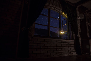 Night scene of stars seen through the window from dark room. Night sky inside dark room.