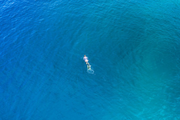 Aerial drone view of a snorkeler over a tropical coral reef