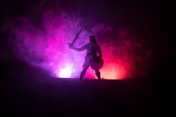 Medieval battle scene. Silhouettes of figures as separate objects, fight between warriors on dark toned foggy background. Night scene.