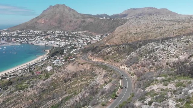 a group of motorcyclists riding down a winding mountainous road next to the sea in Cape Town South Africa