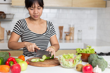 Healthy food Asian woman is cooking salad in kitchen, female preparing the vegetables and fruit at...