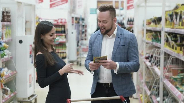 Funny positive video of young happy couple are shopping at supermarket.