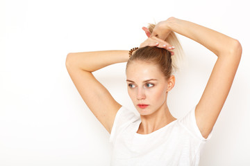Fototapeta premium A young, thoughtful lady brushed her blond long hair back to gather it in a bun.