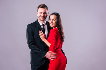 Love you so much! Beautiful stylish and elegant couple in suit and dress are hugging, have a fun and posing isolated in studio. Holidays and events. St Valentine's day. Day of lovers