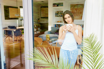 Young woman wearing pajamas while drinking morning coffee at home