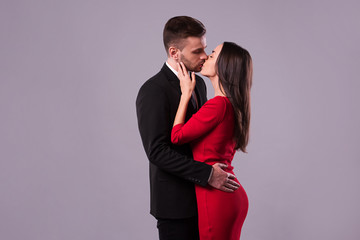 Love you so much! Beautiful stylish and elegant couple in suit and dress are hugging, have a fun and posing isolated in studio. Holidays and events. St Valentine's day. Day of lovers