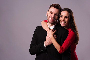 Love you so much! Beautiful stylish and elegant couple in suit and dress are hugging, have a fun and posing isolated in studio. Holidays and events. St Valentine's day. Day of lovers