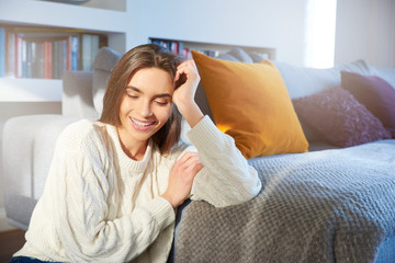 Smiling young woman daydreaming while relaxing at home