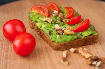 Fototapeta na wymiar Sandwich with avocado tomatoes and nuts. Healthy diet.