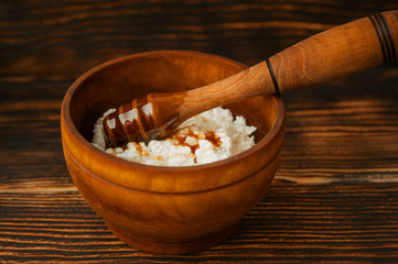 Cottage cheese with honey in a wooden bowl.