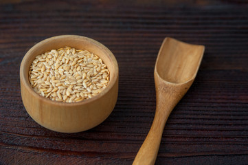 Flax seeds in a wooden bowl and spoon on the table.