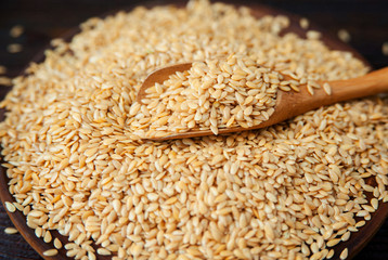 Pile of flax seeds with a wooden spoon on the table.