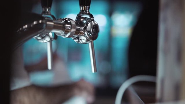 Close-up. Beer tap. Pouring beer in the bar. Compensatory tap for beer. Blurred bar background. Bar counter