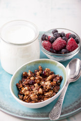 Homemade granola in a bowl  and frozen berries, yogurt in glass jar for breakfast