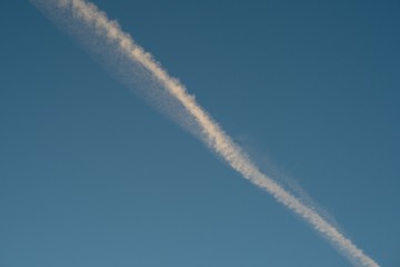 Fototapeta na wymiar Plane flying on a blue sky, condensation line.