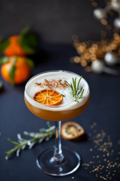 Christmas cocktail of amaretto sour with dehydrated clementine and rosemary