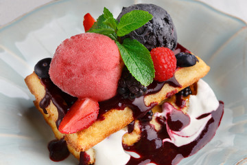 Plate of belgian waffles with ice cream and fresh berries