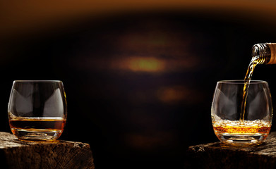 Pour whiskey out of the bottle in whiskey glass in the bar - obrazy, fototapety, plakaty