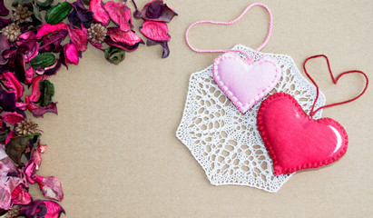 textile hearts on knitted cloth and dry rose petals on a background of cardboard