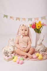Cute funny baby with bunny ears and colorful Easter eggs and rabbits. Easter Baby. Greeting Easter card template. Girl baby in suit of rabbit for Easter. 