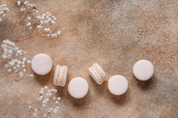 Top view on beige almond french macaroons on a textured background with dried flower. Srping or autumn flat lay composition.