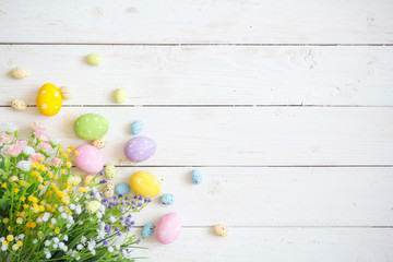 Easter eggs with flowers on white rustic wooden background. View from above
