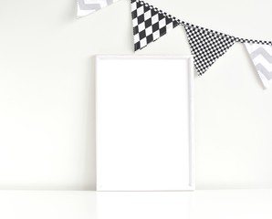 Monochrome nursery frame mockup for artwork or photos on white table, black and white flags garland.