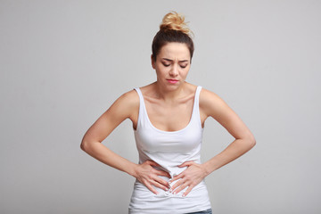 Woman with stomachache, having food poisoning, grey background