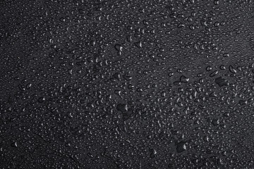 Dark gray black slate background with water drops or natural stone texture.