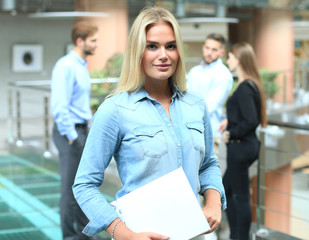 Business woman in casual wear with her staff, people group in background at modern bright office.