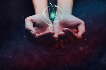 Human hand holding atom on a palm. Nebula dust in infinite space. Mixed media.