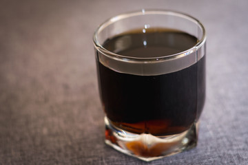 a glass with a dark liquid on a gray background