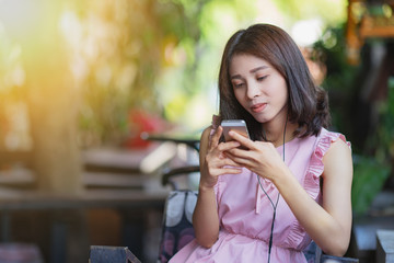 Young beautiful asian woman listening to music from smartphone while relax in cafe with happiness.