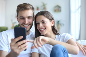 Young couple taking a selfie on couch at home in the living room.