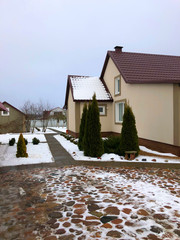 Country cozy house in the Belarusian prairies in winter with Christmas trees on the site