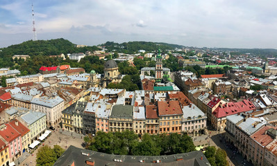 A bird's-eye view of the Ukrainian city of Lviv from the tower of the town hall where you can see the roofs of many houses around and a beautiful landscape